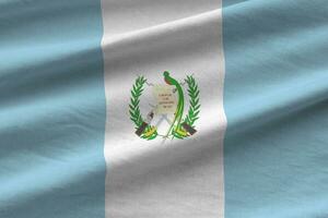 Guatemala flag with big folds waving close up under the studio light indoors. The official symbols and colors in banner photo