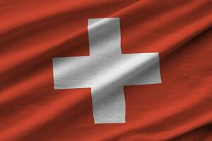 Switzerland flag with big folds waving close up under the studio light indoors. The official symbols and colors in banner photo