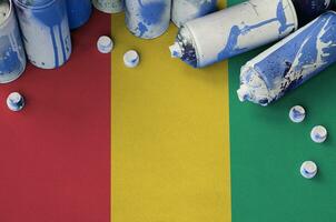Guinea flag and few used aerosol spray cans for graffiti painting. Street art culture concept photo
