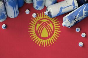 Kyrgyzstan flag and few used aerosol spray cans for graffiti painting. Street art culture concept photo