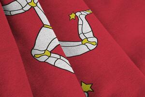 Isle of Man flag with big folds waving close up under the studio light indoors. The official symbols and colors in banner photo