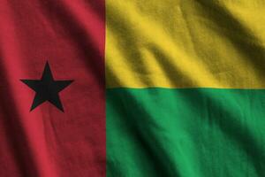 Guinea Bissau flag with big folds waving close up under the studio light indoors. The official symbols and colors in banner photo