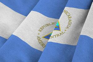 Nicaragua flag with big folds waving close up under the studio light indoors. The official symbols and colors in banner photo