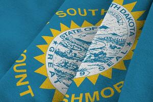 South Dakota US state flag with big folds waving close up under the studio light indoors. The official symbols and colors in banner photo