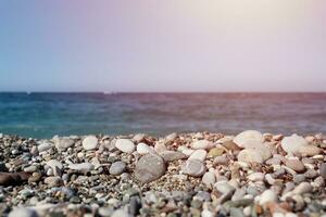 Bank of pebbles with the sea and beach in the background photo