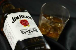 KYIV, UKRAINE - MAY 4, 2022 Jim Beam original alcohol bottle on wooden table with black fabric photo