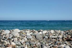 Bank of pebbles with the sea and beach in the background photo