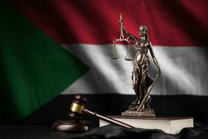 Sudan flag with statue of lady justice, constitution and judge hammer on black drapery. Concept of judgement and guilt photo