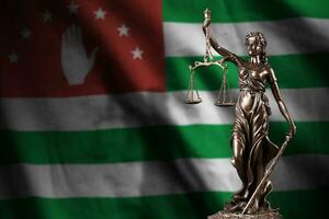 Abkhazia flag with statue of lady justice and judicial scales in dark room. Concept of judgement and punishment photo