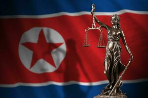 North Korea flag with statue of lady justice and judicial scales in dark room. Concept of judgement and punishment photo