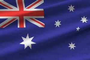 Australia flag with big folds waving close up under the studio light indoors. The official symbols and colors in banner photo