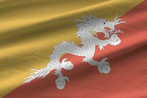 Bhutan flag with big folds waving close up under the studio light indoors. The official symbols and colors in banner photo