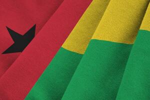 Guinea Bissau flag with big folds waving close up under the studio light indoors. The official symbols and colors in banner photo