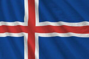 Iceland flag with big folds waving close up under the studio light indoors. The official symbols and colors in banner photo