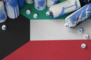 Kuwait flag and few used aerosol spray cans for graffiti painting. Street art culture concept photo