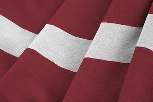 Latvia flag with big folds waving close up under the studio light indoors. The official symbols and colors in banner photo