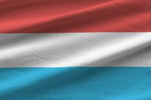 Luxembourg flag with big folds waving close up under the studio light indoors. The official symbols and colors in banner photo