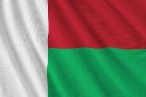 Madagascar flag with big folds waving close up under the studio light indoors. The official symbols and colors in banner photo