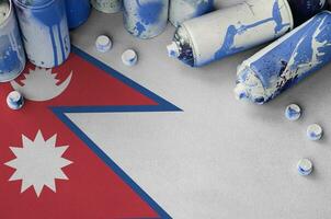 Nepal flag and few used aerosol spray cans for graffiti painting. Street art culture concept photo