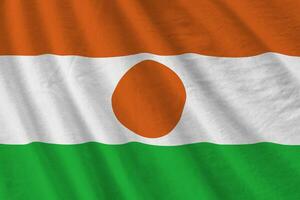 Niger flag with big folds waving close up under the studio light indoors. The official symbols and colors in banner photo