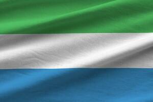 Sierra Leone flag with big folds waving close up under the studio light indoors. The official symbols and colors in banner photo