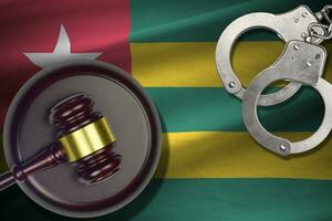 Togo flag with judge mallet and handcuffs in dark room. Concept of criminal and punishment, background for judgement topics photo