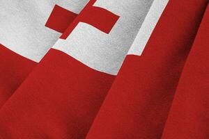 Tonga flag with big folds waving close up under the studio light indoors. The official symbols and colors in banner photo