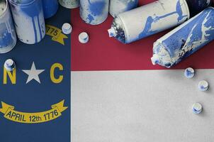 North Carolina US state flag and few used aerosol spray cans for graffiti painting. Street art culture concept photo
