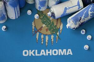 Oklahoma US state flag and few used aerosol spray cans for graffiti painting. Street art culture concept photo