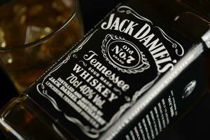 KYIV, UKRAINE - MAY 4, 2022 Jack Daniels original alcohol bottle on wooden table with black fabric photo