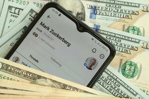 KYIV, UKRAINE - JULY 7, 2023 Threads by Meta application on display of Samsung smartphone and many dollar bills photo