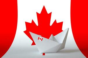 Canada flag depicted on paper origami ship closeup. Handmade arts concept photo