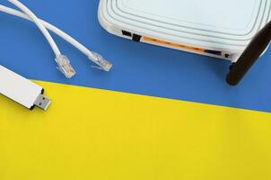 Ukraine flag depicted on table with internet rj45 cable, wireless usb wifi adapter and router. Internet connection concept photo