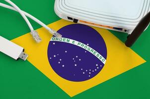 Brazil flag depicted on table with internet rj45 cable, wireless usb wifi adapter and router. Internet connection concept photo