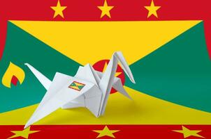 Grenada flag depicted on paper origami crane wing. Handmade arts concept photo