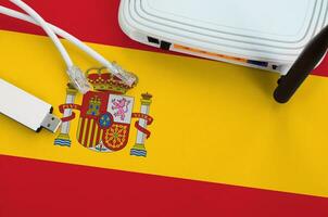 Spain flag depicted on table with internet rj45 cable, wireless usb wifi adapter and router. Internet connection concept photo
