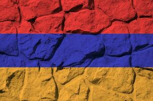 Armenia flag depicted in paint colors on old stone wall closeup. Textured banner on rock wall background photo