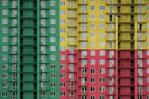 Benin flag depicted in paint colors on multi-storey residental building under construction. Textured banner on brick wall background photo