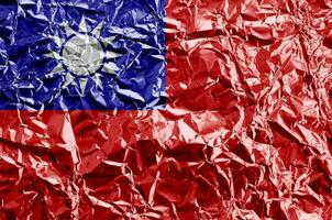 Taiwan flag depicted in paint colors on shiny crumpled aluminium foil closeup. Textured banner on rough background photo