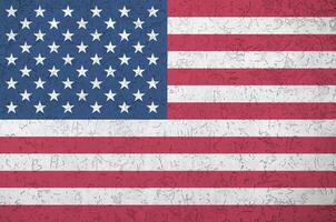 United States of America flag depicted in bright paint colors on old relief plastering wall. Textured banner on rough background photo