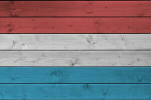 Luxembourg flag depicted in bright paint colors on old wooden wall. Textured banner on rough background photo