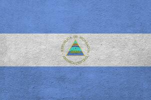 Nicaragua flag depicted in bright paint colors on old relief plastering wall. Textured banner on rough background photo