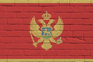 Montenegro flag depicted in paint colors on old brick wall. Textured banner on big brick wall masonry background photo