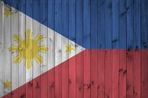 Filipinas bandera representado en brillante pintar colores en antiguo de madera pared. texturizado bandera en áspero antecedentes foto