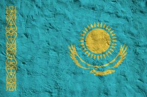 Kazakhstan flag depicted in bright paint colors on old relief plastering wall. Textured banner on rough background photo