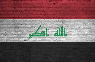 Irak bandera representado en pintar colores en antiguo ladrillo pared. texturizado bandera en grande ladrillo pared albañilería antecedentes foto