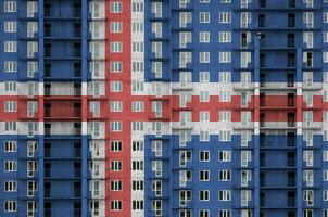 Iceland flag depicted in paint colors on multi-storey residental building under construction. Textured banner on brick wall background photo