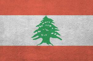 Lebanon flag depicted in bright paint colors on old relief plastering wall. Textured banner on rough background photo