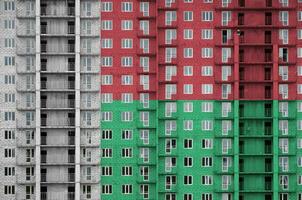 Madagascar flag depicted in paint colors on multi-storey residental building under construction. Textured banner on brick wall background photo