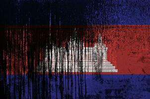 Cambodia flag depicted in paint colors on old and dirty oil barrel wall closeup. Textured banner on rough background photo